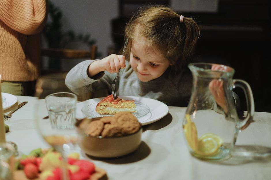 A child joyfully eats homemade pastry at a cozy dining table setting.