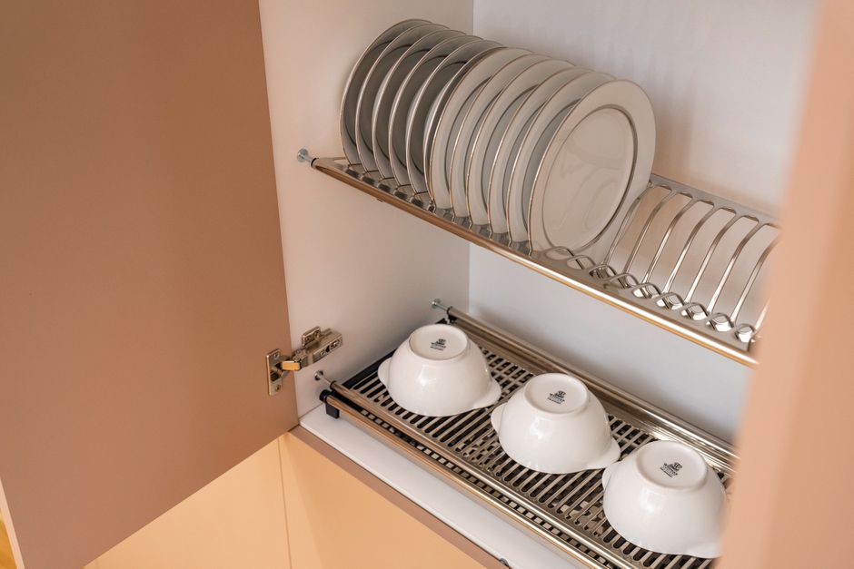 A clean and organized kitchen cabinet displaying plates and bowls on a drying rack.