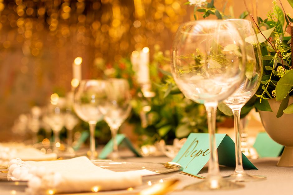 A close-up of a beautifully decorated table with wine glasses, candles, and greenery, perf