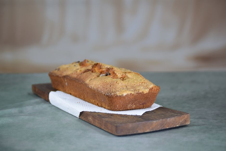 A homemade banana bread loaf on a rustic wooden board, showcasing texture and warmth.