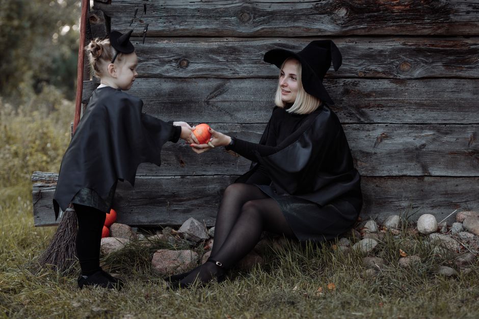 A mother and child dressed as witches share a moment during a Halloween celebration outdoo