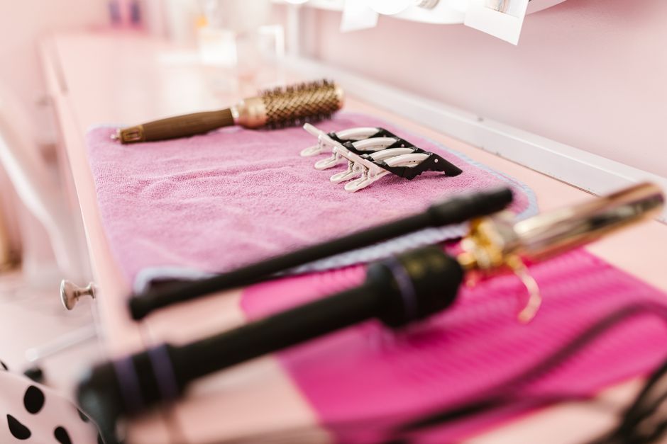 A selection of hair styling tools arranged on a pink towel in a salon setting, ready for u