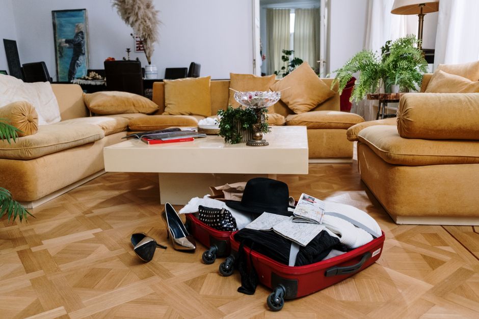 A stylish living room with beige couches and an open suitcase on a parquet floor, surround