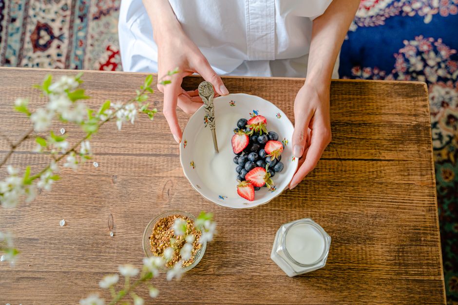 A top view of a person preparing a healthy breakfast with fresh berries, milk, and granola