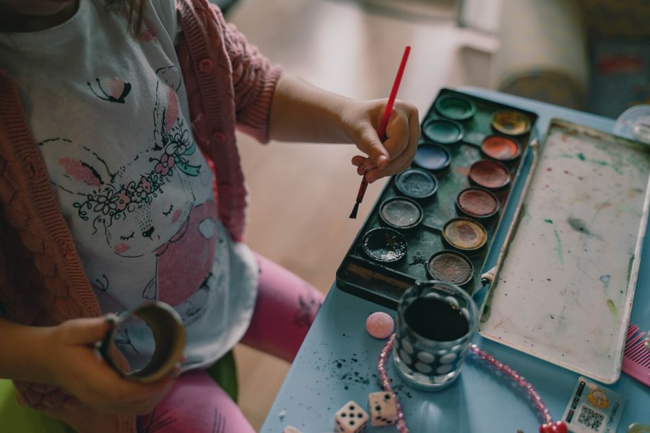 A young child painting with watercolors, wearing a cute printed shirt, engaging in creativ