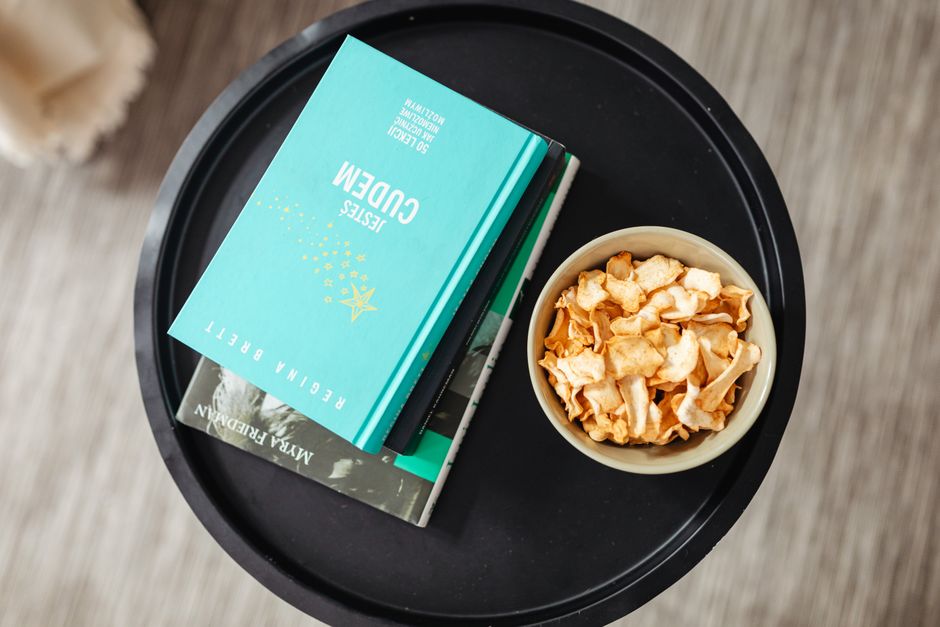 Aerial view of a stack of books and a snack bowl on a round table, creating a cozy reading nook.