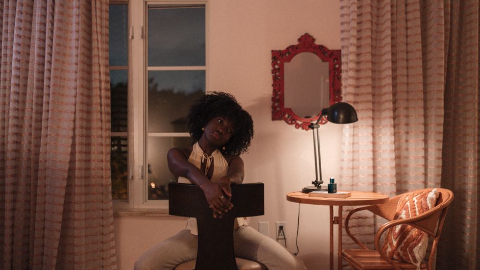 A woman seated indoors at night, exuding a calm and reflective mood.