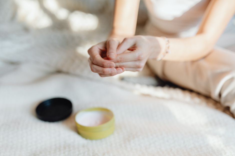 Close-up of a woman applying hand cream in a softly lit indoor setting, emphasizing skinca