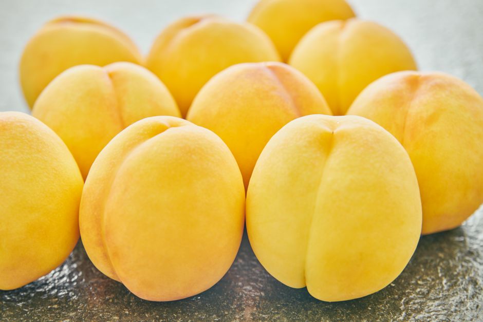 Close-up of ripe peaches on a textured countertop, showcasing freshness and vibrant color.