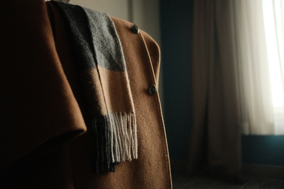 Cozy camel coat with wool scarf draped, showcasing winter fashion indoors.