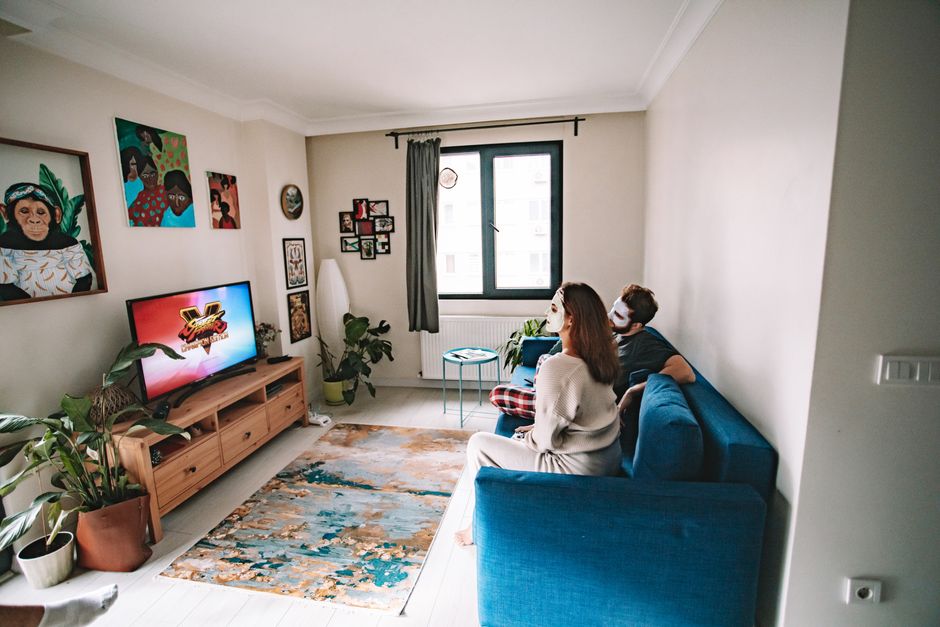 A couple enjoying relaxation time in a stylish living room with indoor plants and TV entertainment.