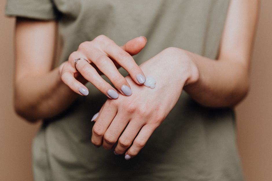 Crop anonymous female in casual shirt with manicured hands and ring softly rubbing hand mo