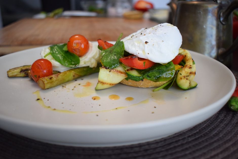 Delicious breakfast with poached egg, grilled asparagus, and cherry tomatoes on a ceramic 