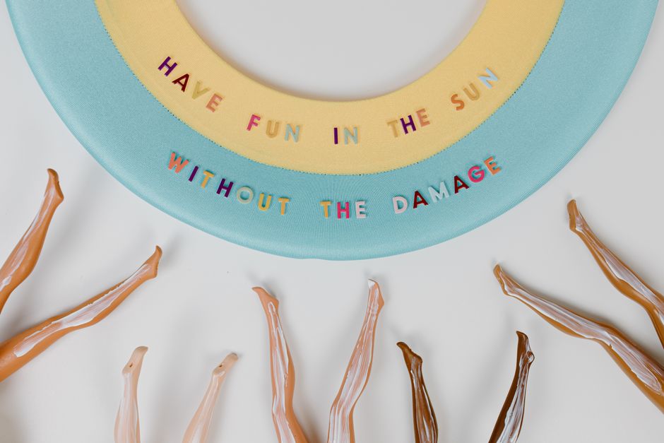 Conceptual image promoting sunscreen use, featuring doll legs and sun hat with fun text.