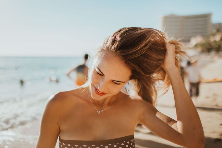 Woman in bikini smiling and enjoying a sunny day at the beach.
