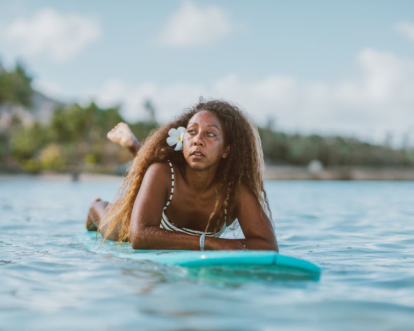 A woman relaxing on a surfboard in a tropical setting, embodying summer vibes.