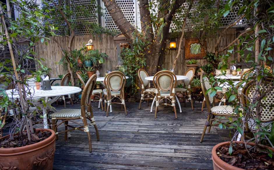 A quaint outdoor cafe setting with wooden chairs and lush greenery, perfect for relaxation.