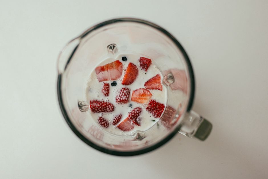 Fresh strawberries and milk in a blender viewed from above, perfect for healthy eating con