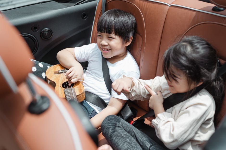 From above smiling ethnic boy and girl in casual outfits sitting fastened in passenger sea