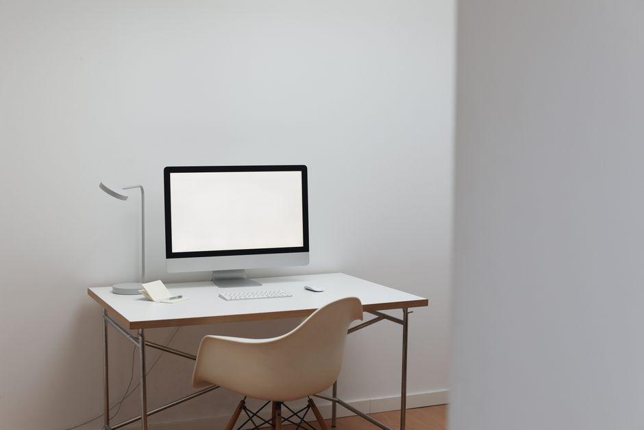 Interior of room in minimal design with modern computer on white table and comfortable cha