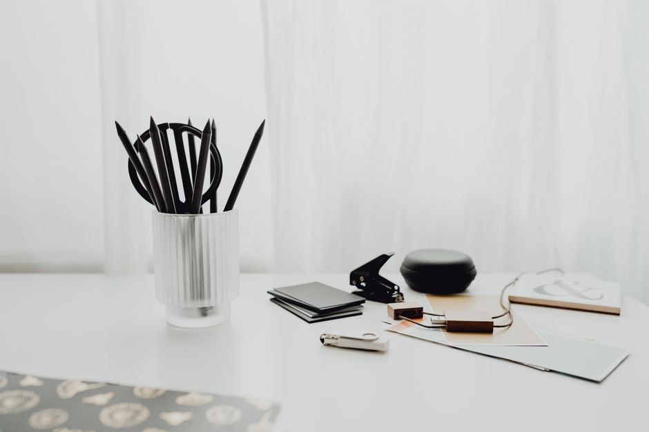 A clean white desk setup with office supplies and stationery in a minimalist style.