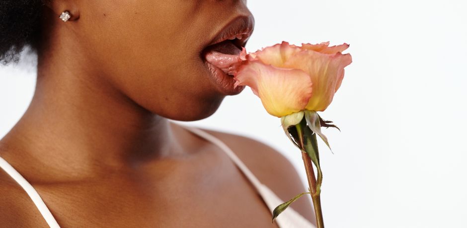 African American woman in a studio with rose, conveying fresh and vibrant emotions.