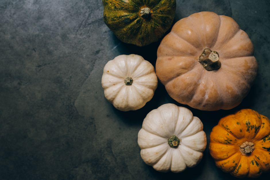 Overhead view of assorted colorful pumpkins on a dark concrete surface, ideal for autumn t