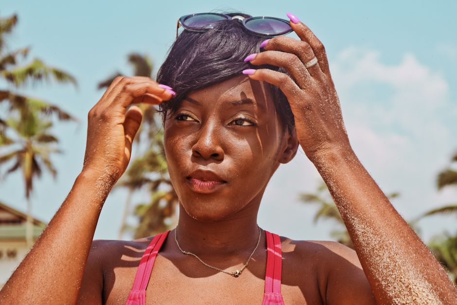 Portrait of a relaxed woman with sunglasses at a sunny tropical beach, enjoying the warm c