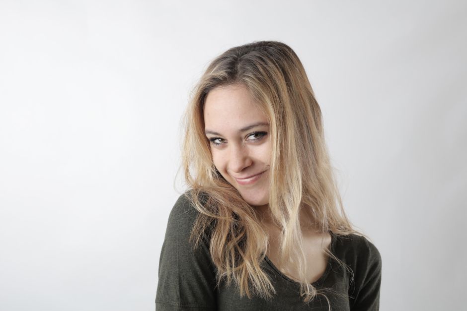 Close-up portrait of a blonde woman smiling with a white background.