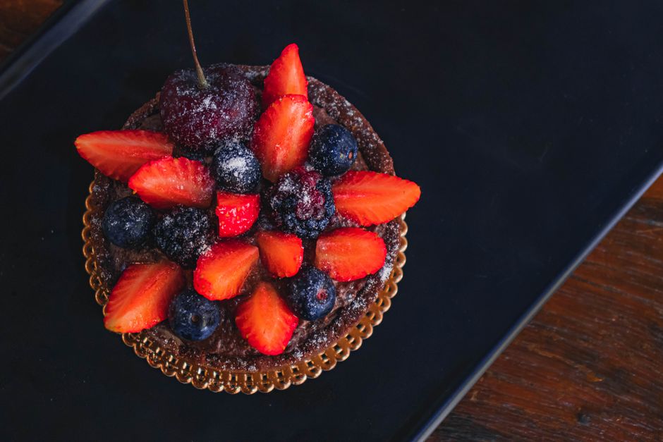 A close-up of a luscious chocolate tart topped with fresh strawberries and blueberries.