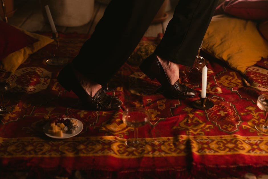 Sophisticated ambiance with leather shoes tiptoeing on a vibrant bohemian rug lit by candlelight.