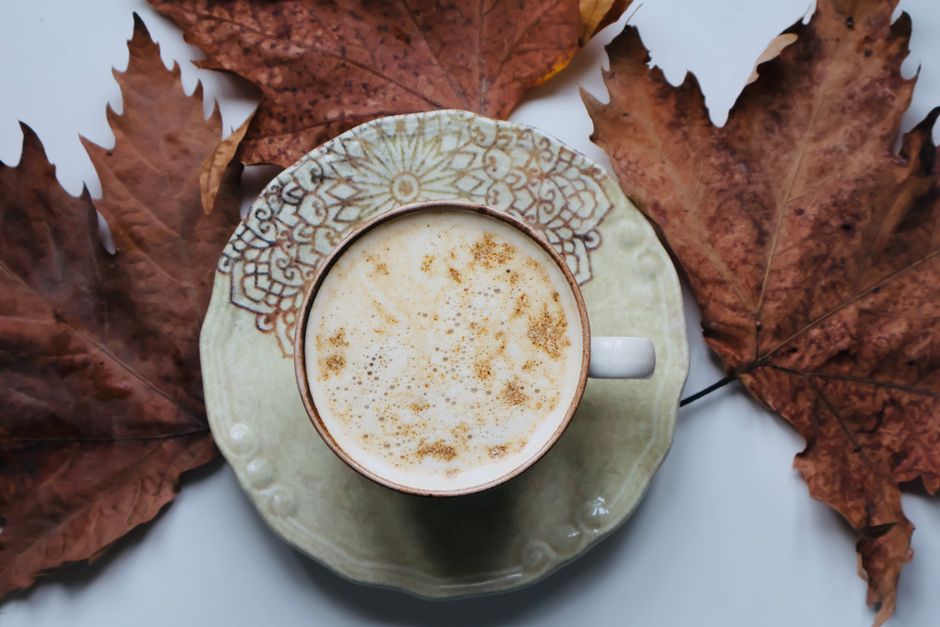 Warm autumn coffee with rustic cup surrounded by brown leaves, perfect for fall vibes.